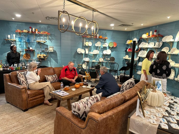 People sitting on brown leather couches surrounds by blue walls with dishware on shelving